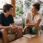 Mother and teenage son having an open, engaged conversation on a sofa